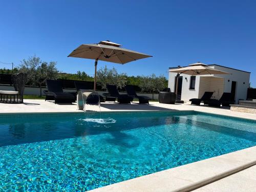a swimming pool with chairs and an umbrella at Villa DEL SOLE with Heated Saltwater Pool, Jacuzzi and Sauna in Ljubuški