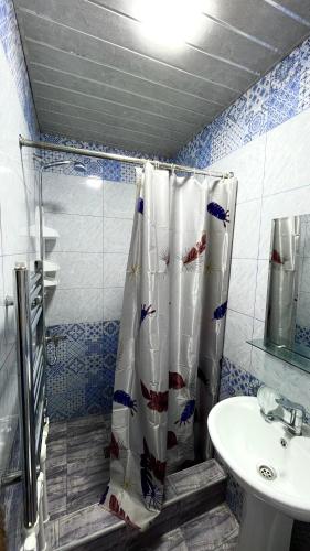 a bathroom with a shower curtain and a sink at Ners House in Garni