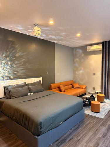a bedroom with a bed and an orange couch at YourHome - Stay & More in Hoàng Mai