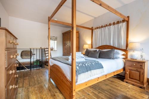 a bedroom with a canopy bed and a wooden floor at Potter's Wheel, by the lake in High Nibthwaite
