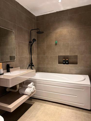 a bathroom with a bath tub and a sink at YourHome - Stay & More in Hoàng Mai