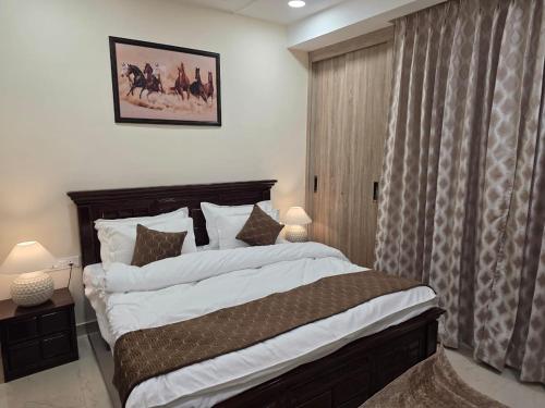 a bedroom with a large bed with white sheets and pillows at Ganges Abode in Haridwār