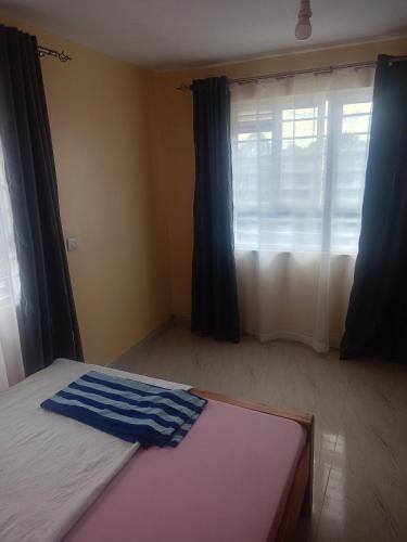 a bedroom with a bed and a window with curtains at Kibwezi Penthouse in Libwezi