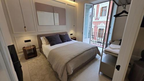 a bedroom with a bed with blue pillows and a balcony at LOS CUATRO CANTONES, Centro Ciudad in Palencia