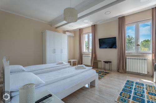 a white bedroom with two beds and a tv at Vila Eleonora Beograd in Belgrade