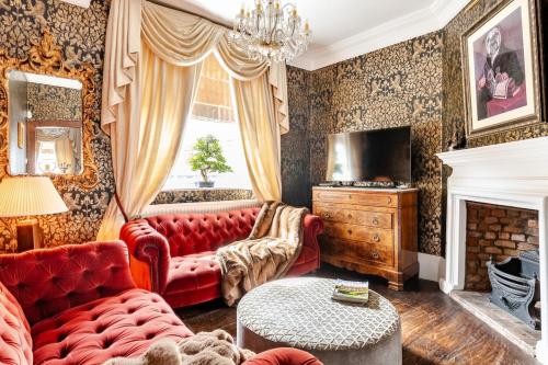 a living room with a red couch and a fireplace at Warwick Centre Townhouse Castle views in Warwick