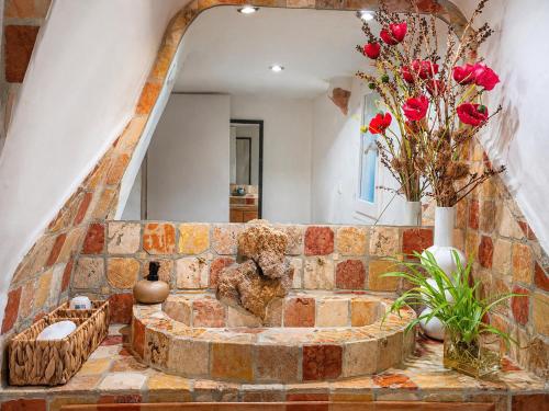 a bathroom with a stone wall with a mirror and flowers at Salvacintoggio -Votre Villa avec Piscine Privée- in Porto-Vecchio