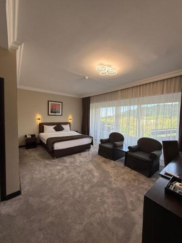 a large bedroom with a bed and a couch and chairs at Premier Alatau Hotel in Almaty