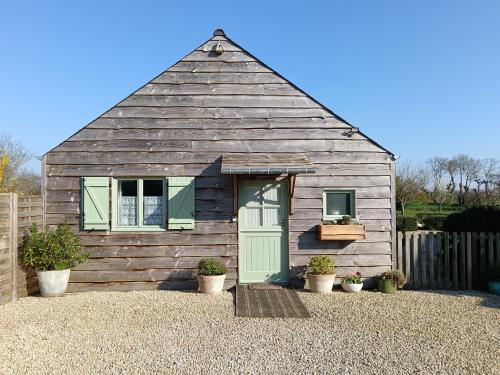 a small wooden house with a green door and plants at Charming Countryside Chalet in Mégrit