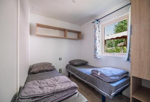 two beds in a room with a window at Camping Le Paradis Médoc in Saint-Laurent-de-Médoc