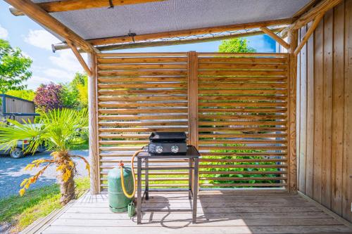 a wooden pergola with a table with a radio on it at Camping Le Paradis Médoc in Saint-Laurent-de-Médoc