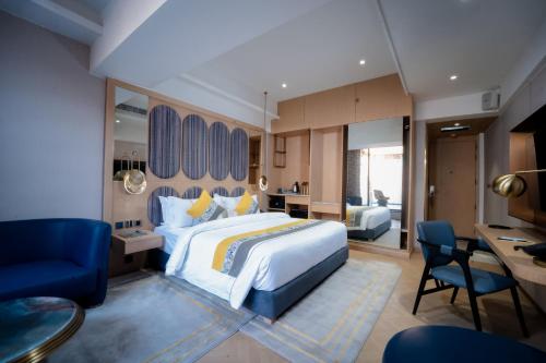a bedroom with a large bed and a desk and chairs at The Panache Kautilya in Patna