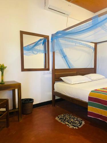 a bedroom with a bed and a window and a table at Baywings Rooms in Arugam Bay