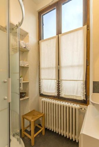 a bathroom with a radiator and a window and a stool at La Palette Fleurie in Laignes