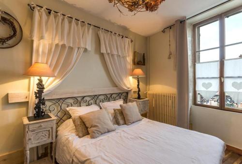 a bedroom with a bed with white sheets and a window at La Palette Fleurie in Laignes