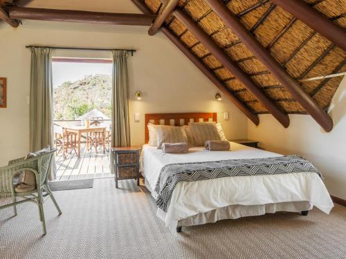 a bedroom with a large bed and a balcony at Tides River Lodge in Malgas