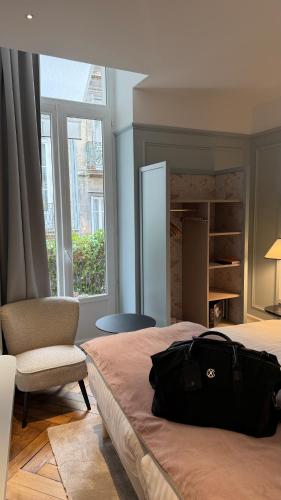 a bedroom with a bag on a bed and a chair at Boutique Hôtel Le Clos Huguerie - Bordeaux Centre in Bordeaux