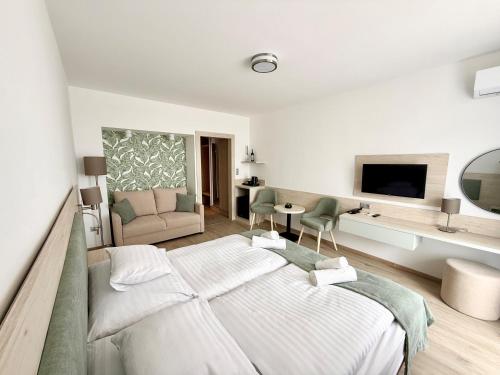 a white bedroom with a bed and a living room at Apartman Hotel in Bük
