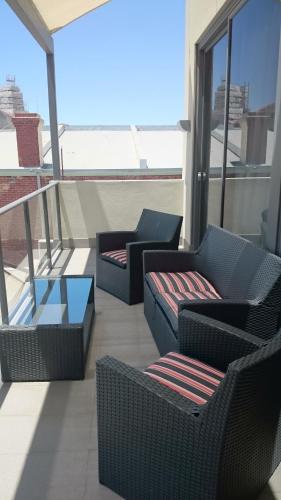 a balcony with two chairs and tables on a building at New Haus by Hougoumont Hotel, former Bannister 22 in Fremantle