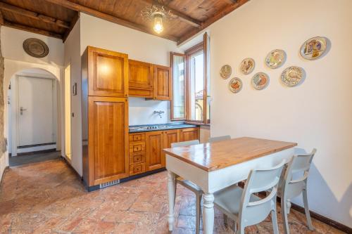 a kitchen with wooden cabinets and a table and chairs at Historic Borgo Lake Como Campidoglio 5 in Lenno