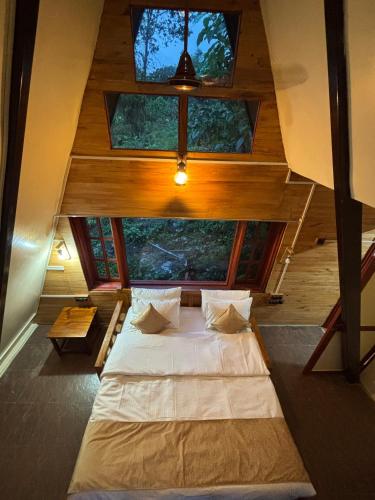 a large bed in a room with some windows at Hotel YAN Residency Bhimtal - Nainital in Bhīm Tāl
