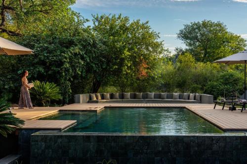 a woman walking next to a swimming pool at Ujima Lodge in Hoedspruit