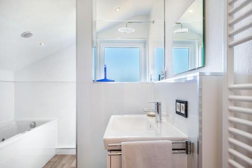 a white bathroom with a sink and a mirror at Haus Gutach in Schönwald