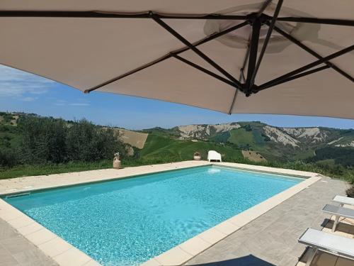 a swimming pool with an umbrella and mountains in the background at Villa Ferranti Abruzzo in Montefino