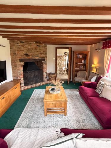 a living room with a couch and a fireplace at Mesopotamia Cottage in Clifton Hampden