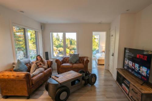 a woman sitting on a couch in a living room at Chalet Luméo Private SPA, Golf & carling Lake in Brownsburg