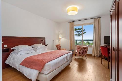 a bedroom with a bed and a desk and a window at Hotel Le Bellevue, Demeures & Chateaux in Villerville