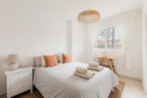 a white bedroom with a bed with towels on it at ALOJAMIENTO ARENAL PARK in Jávea