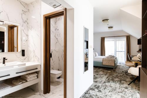a bathroom with a sink and a toilet and a bedroom at KQC Boutique Villa in Balatonlelle