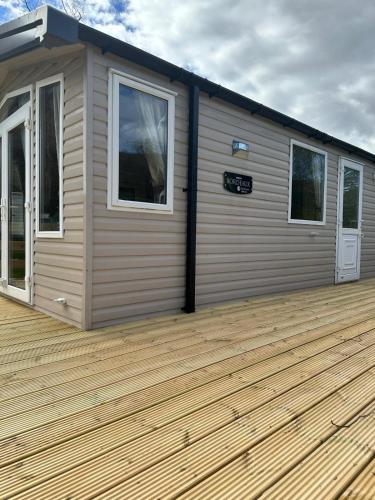 a cabin with a wooden deck with two windows at Swift Bordeaux 56 in Dunoon