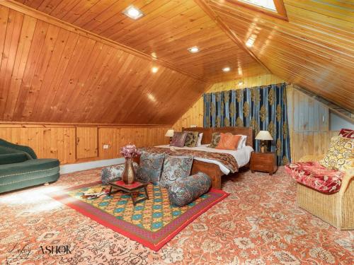 a bedroom with a bed and a couch and a chair at Luxury Ashok Cottage in Srinagar
