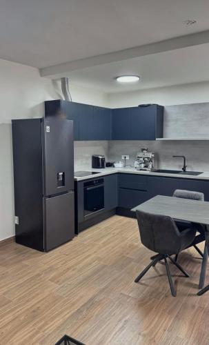 a kitchen with blue cabinets and a table and a refrigerator at apartment R in Mrljane