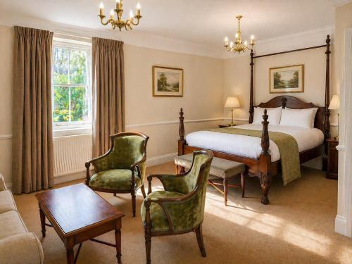 a bedroom with a bed and chairs and a couch at Nent Hall Country House Hotel in Nenthead