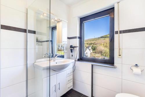 a white bathroom with a sink and a window at Ferienwohnung Landblick in Brilon