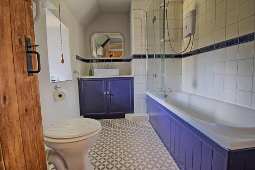 a bathroom with a toilet and a tub and a sink at Martie Cottage - cosy cottage idyllic village in Whitcombe