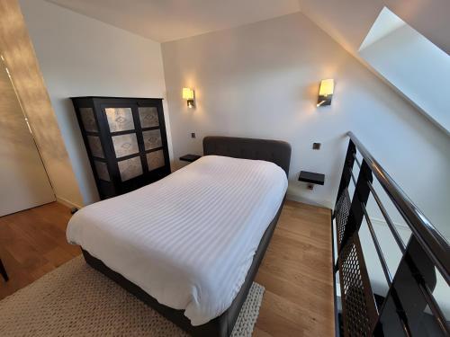 a bedroom with a white bed in a stair case at Couleur océan, piscine et plage in Le Croisic