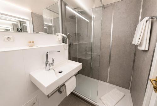 a white bathroom with a sink and a shower at CityHotel Feuerbach in Stuttgart