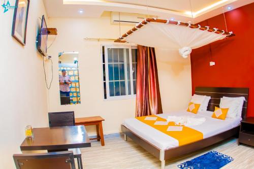 a bedroom with a bed and a table and a desk at Salama Hôtel Majunga in Mahajanga