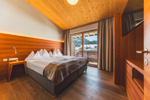 a bedroom with a bed and a large window at Mats Lech Alpenquartier in Lech am Arlberg