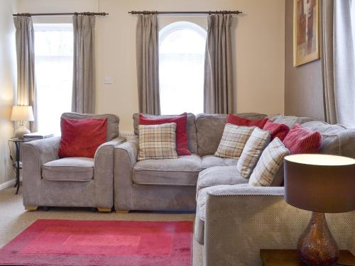 a living room with a gray couch with red pillows at Eldin Hall Cottage 2 - Uk2484 in Scarborough