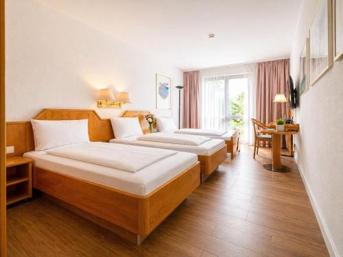 a hotel room with three beds and a table at CityHotel Feuerbach in Stuttgart
