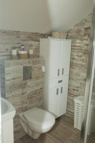 a bathroom with a white toilet and a cabinet at Apartmani Romansa in Irig
