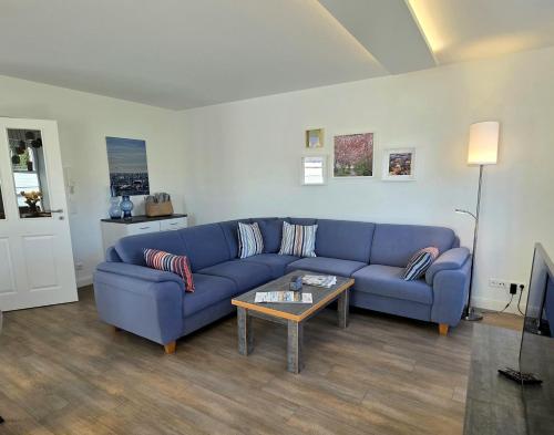 a living room with a blue couch and a table at Meiereikoppel 11 in Petersdorf auf Fehmarn