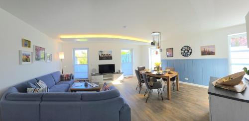 a living room with a blue couch and a table at Meiereikoppel 11 in Petersdorf auf Fehmarn