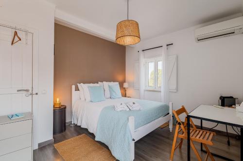 a white bedroom with a bed and a table at Cozy Suite À Da Marina in Quinta do Poço