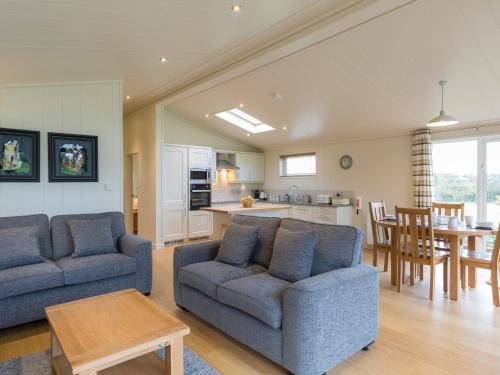 a living room with two blue couches and a kitchen at Maple Lodge in Hassocks